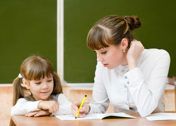 Teacher helping young girl with writing lesson